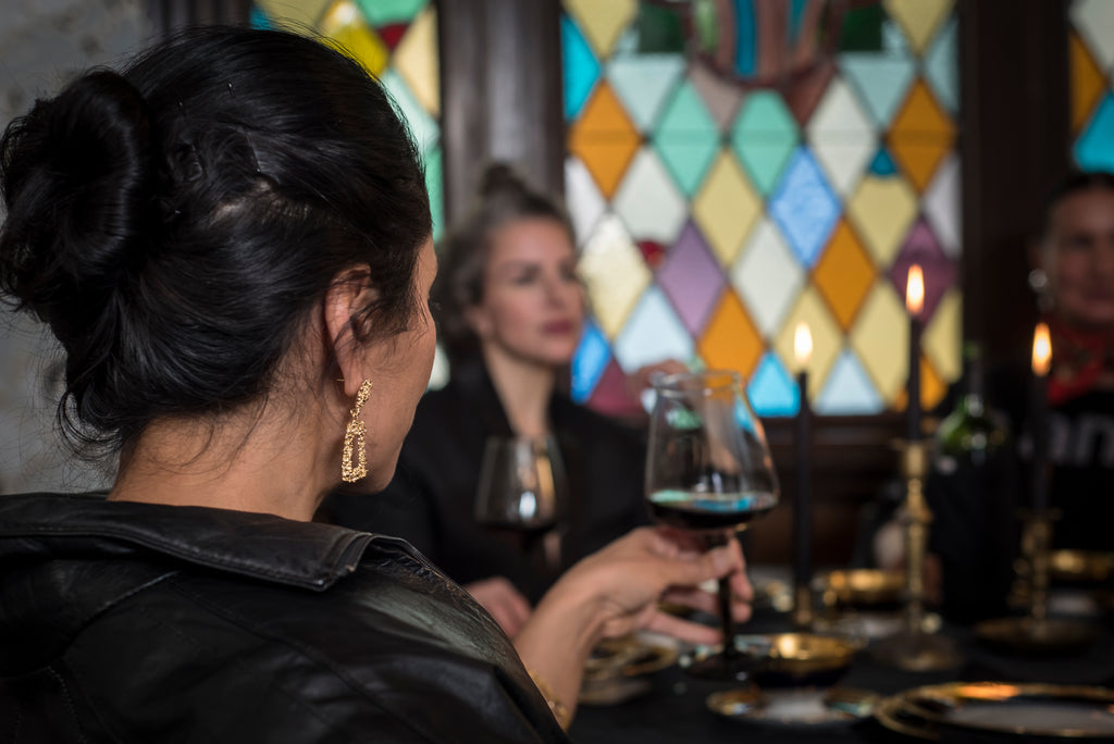 Woman holding a glass of wine in a dimly lit room with stained glass windows.