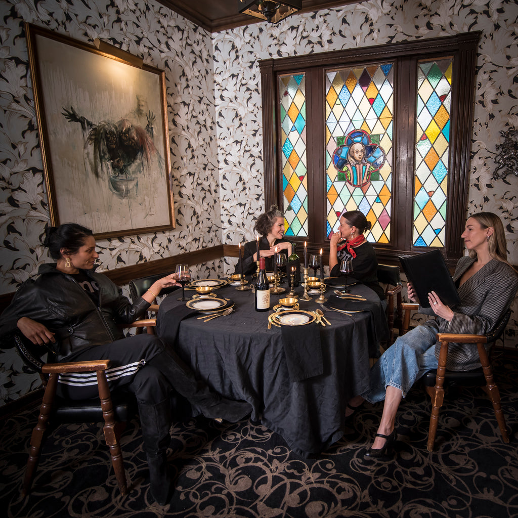 Three women sitting at a table in a restaurant with stained glass window